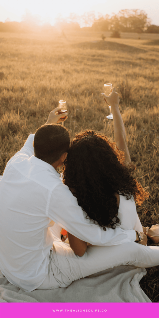 couple in a field toasting each other with wine | How To Manifest The Love You Deserve in 2025 | The Aligned Life Manifestation Blog