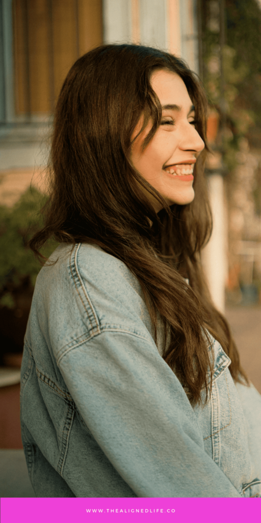 brunette woman in denim jacket smiling | How To Let Go To Manifest | The Aligned Life Manifestation Blog