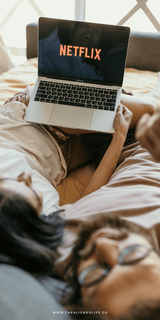 couple watching Netflix on a laptop in bed | Spiritual Shows To Watch On Netflix | The Aligned Life Manifestation Blog