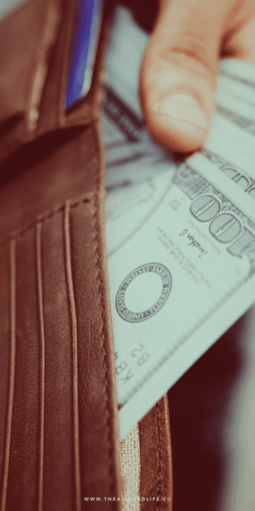 hands pulling money out of a brown wallet | Clear Your Money Blocks FAST | The Aligned Life Manifestation Blog