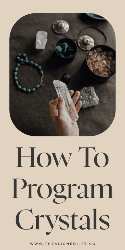 hand over a dark wood table holding a crystal | How To Cleanse, Charge & Program Crystals | The Aligned Life Manifestation Blog