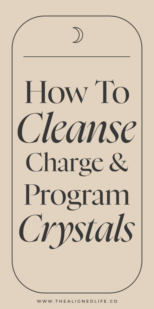 hand over a dark wood table holding a crystal | How To Cleanse, Charge & Program Crystals | The Aligned Life Manifestation Blog