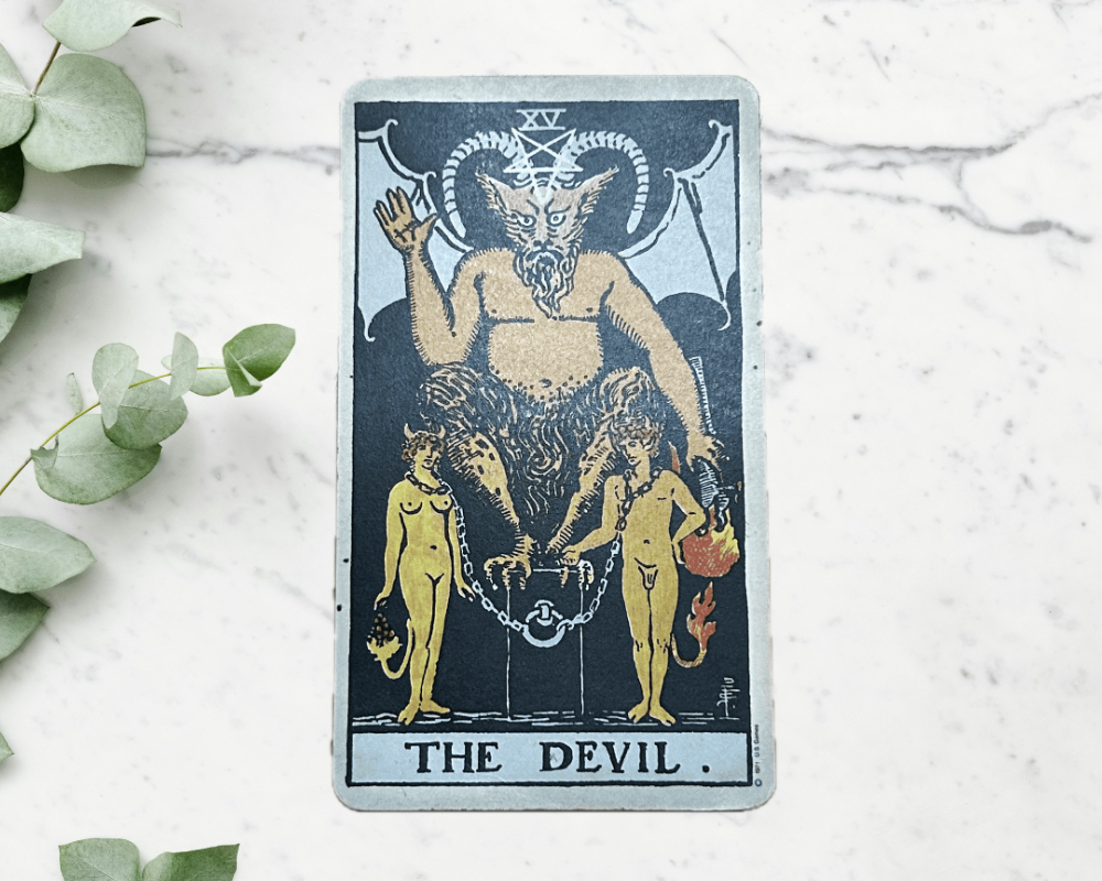white marble table with eucalyptus & The Devil Tarot Card 15