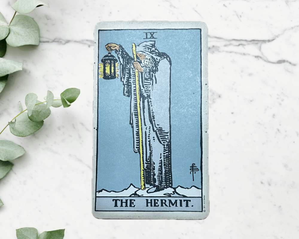 white marble table with eucalyptus & The Hermit Tarot Card 9